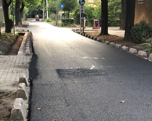 Frissen aszfaltozott utca természetes kőszegéllyel, fasorral szegélyezve