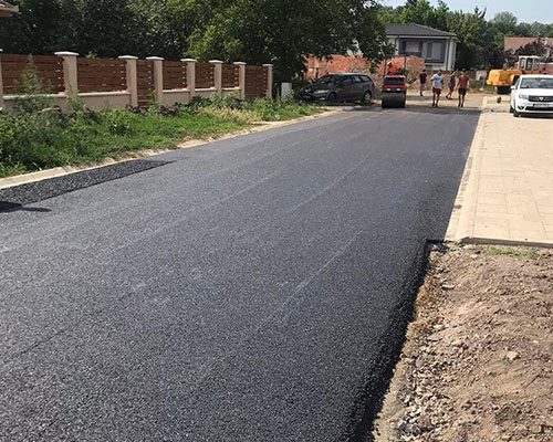 Lakóutca aszfaltozása szegélyek között, hengerléssel