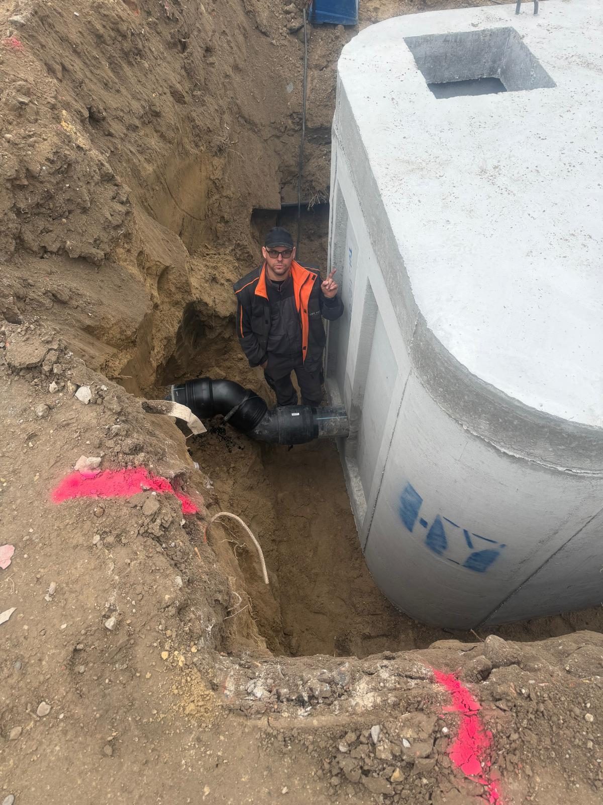 Szakember a munkaárokban: vízzáró betonakna és PE nyomóvezeték bekötése